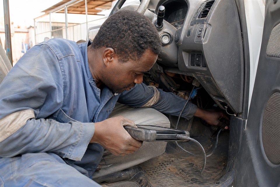 Technician connecting diagnostic equipment inside a vehicle