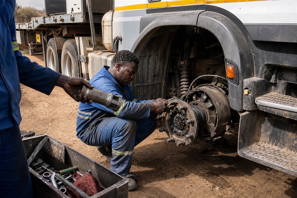 Technicians servicing the exposed wheel hub of a heavy truck
